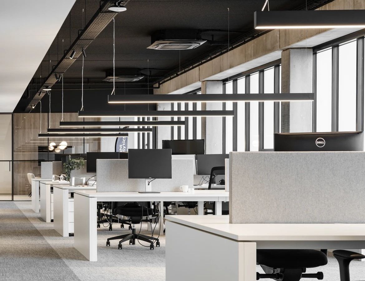 Open-plan commercial office with linear pendant lighting and ceiling cassette air conditioning